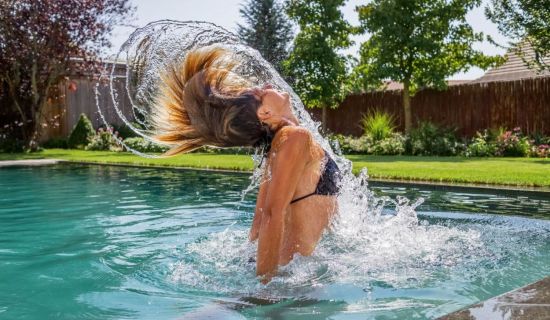 Frau taucht aus Wasser im Schwimmteich auf