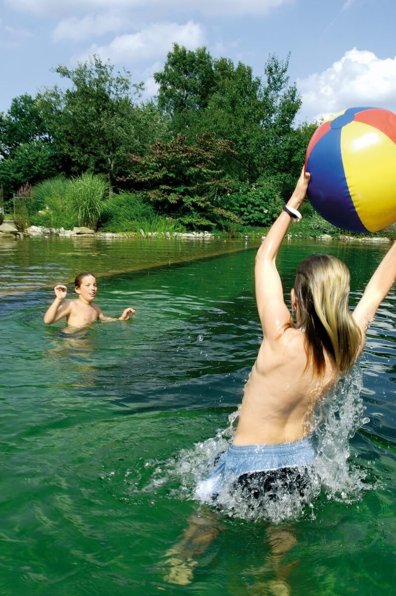 Kinder spielen Wasserball im Schwimmteich