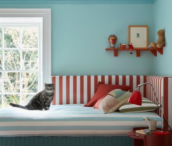 Kinderzimmer mit hellblauer Wand und rot-weißem Bett