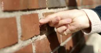 Hand prüft den Mörtel im Backsteinmauerwerk