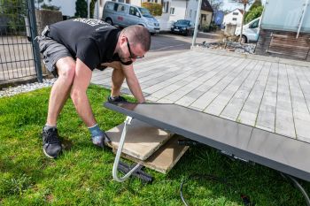 Mann beschwert aufgeständerte Solaranlage mit Fliesen