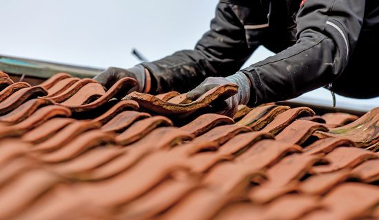 Mann richtet verschobene Dachziegel