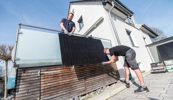 Zwei Männer montieren eine Solaranlage am Balkon