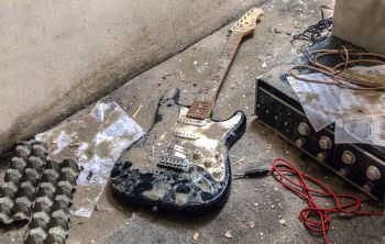 Verschlammte E-Gitarre und Musikgeräte nach einer Überschwemmung