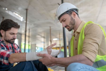 Ein Bauhelfer verbindet einem anderen Bauhelfer die Hand